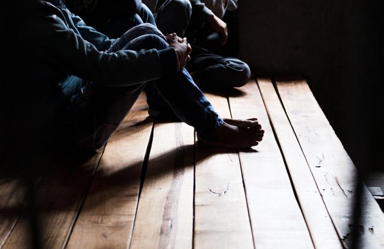 Man sits in shadow in prison cell