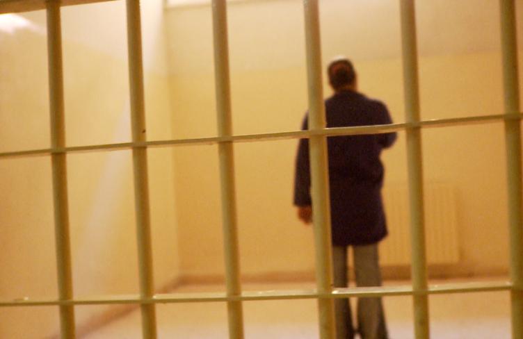 A woman stands alone in a cell
