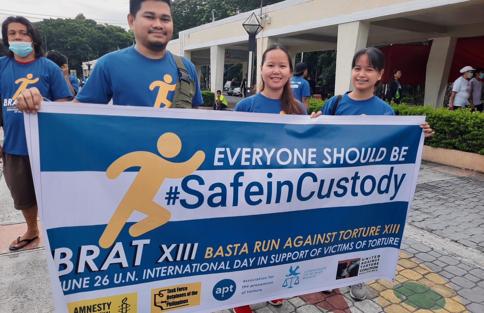 Three "Basta Run" participants holding a Safe In Custody poster