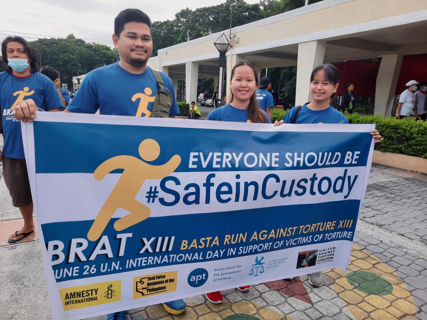 Three "Basta Run" participants holding a Safe In Custody poster